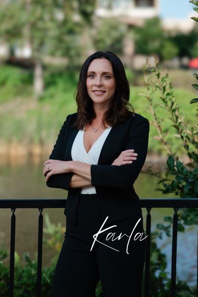 Karla Newton, arms crossed, standing by the water